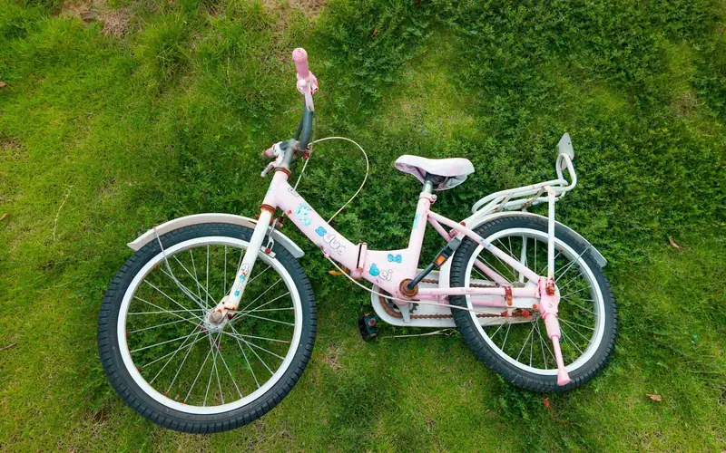 Witte kinderfiets met roze accenten ligt op het gras